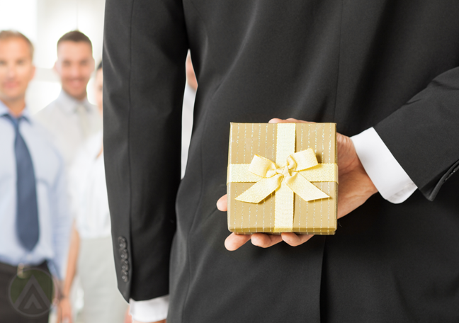 gift in gold wrap held by businessman on back hidden from employees