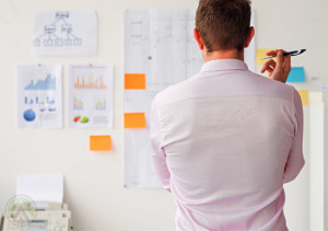 male-call-center-agent-looking-at-reports-on-the-wall