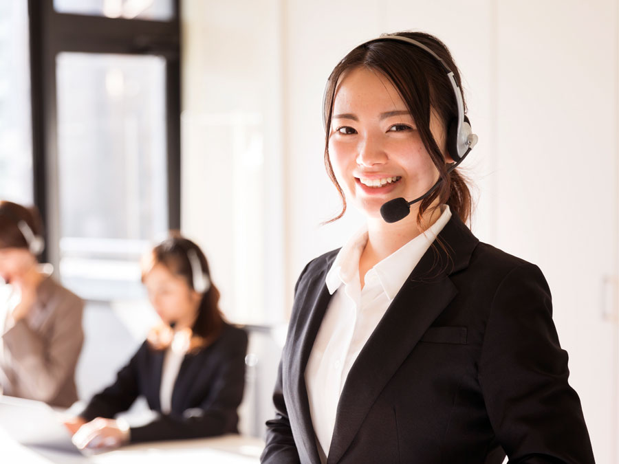 smiling japanese call center agent with customer support coworkers