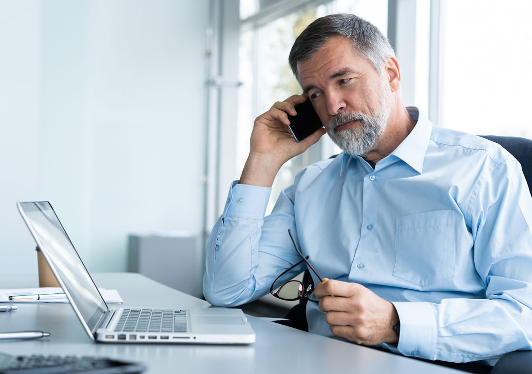 businessman on the phone talking to customer service using laptop to answer survey