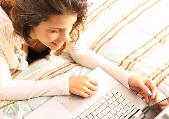 female-customer-on-bed-looking-on-her-laptop