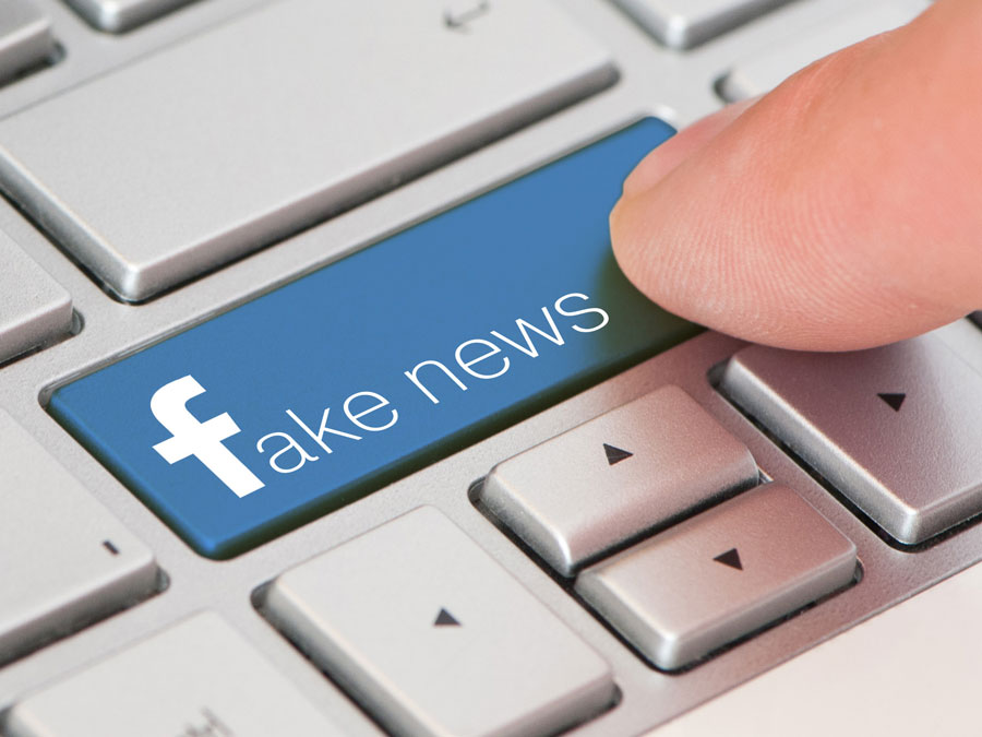 crowdsourcing content moderation depiction finger pressing fake news facebook laptop button
