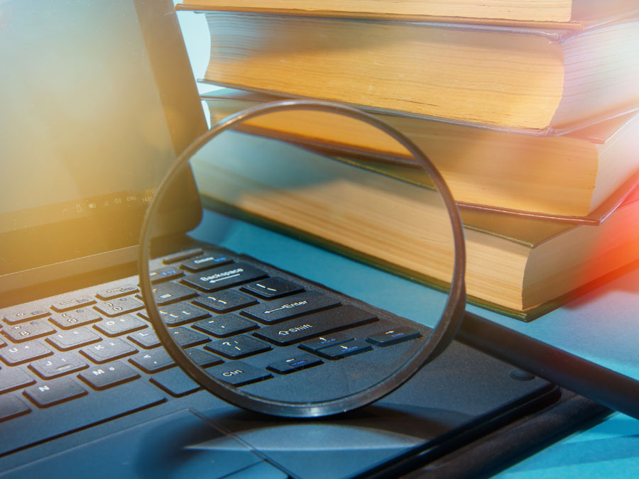 magnifying lens on laptop with books