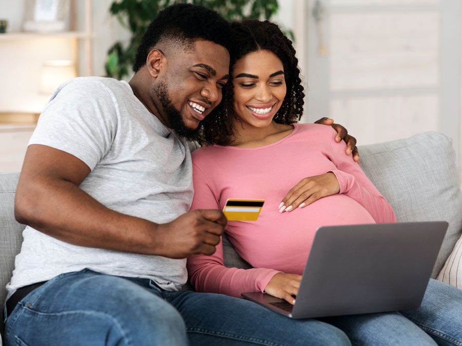 happy young couple pregnant woman using laptop for online shopping