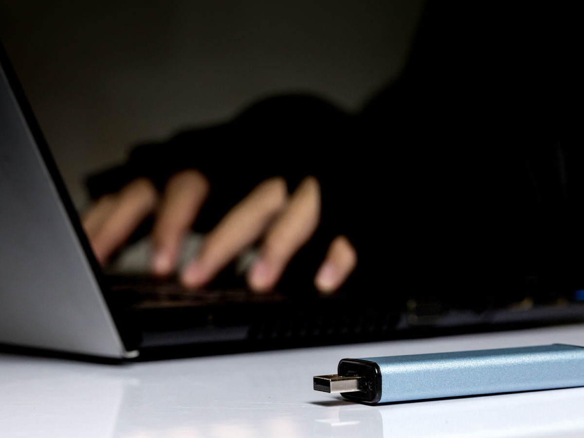 malware infected USB flash drive near laptop used by hacker