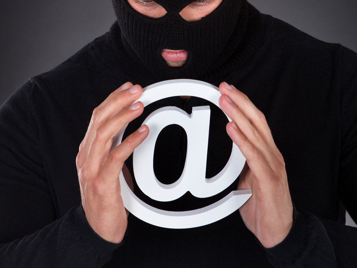 social engineering techniques depiction cybercriminal in ski mask holding email