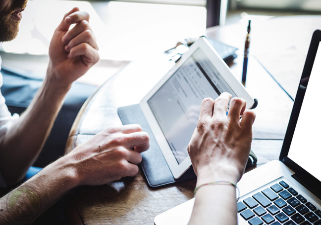 businessmen-looking-through-documents-websites-on-laptop-ad-tablets