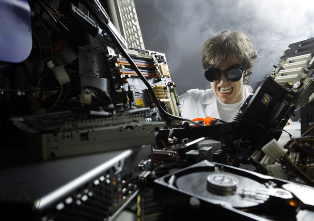 male-scientist-surrounded-by-broken-computer-hardware