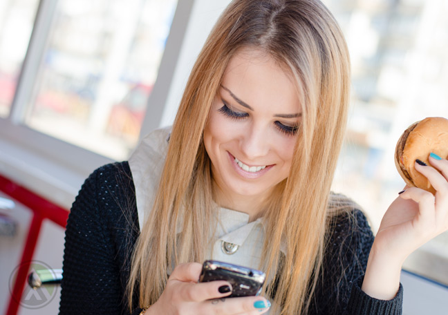 blond-females-using-sms-smartphone-while-having-a-burger