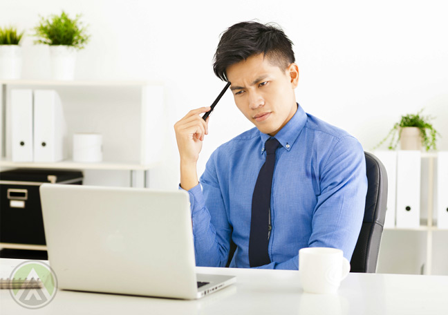 male-asian-businessman-thinking-in-front-of-laptop