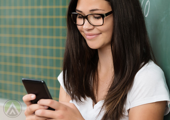 smiling-girl-in-glasses-uwing-smartphone