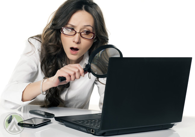 confused-female-employee-searching-on-laptop-with-magnifying-lens