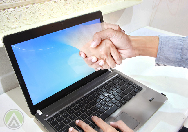 hand-reaching-out-of-laptop-to-shake-businessman-hands