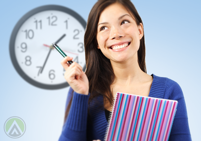 brunette-woman-smiling-holding-notebook-pointing-pen-to-wall-clock