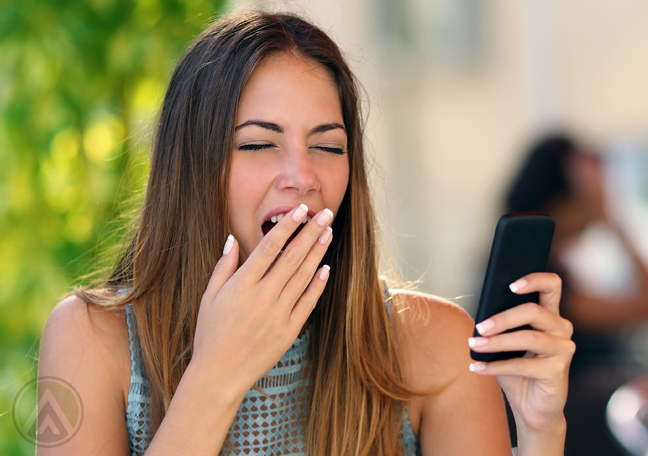 female-yawning-holding-smartphone