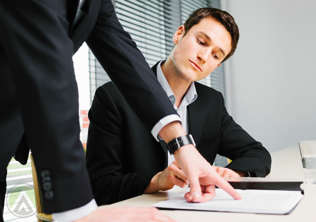 male-millennial-employee-looking-at-document-pointing-boss