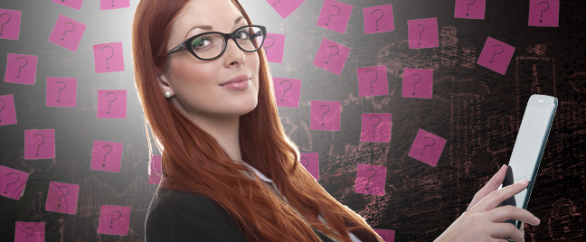 smiling-redhead-employee-in-glasses-using-a-tablet-surrounded-by-postits-wht-questions-marks