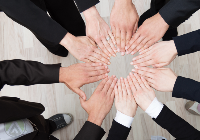 young-millennial-employees-huddled-together-holding-hands-team-work