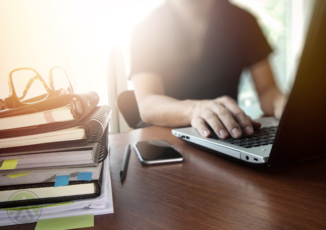 young-man-using-laptop-with-smartphone-and-books