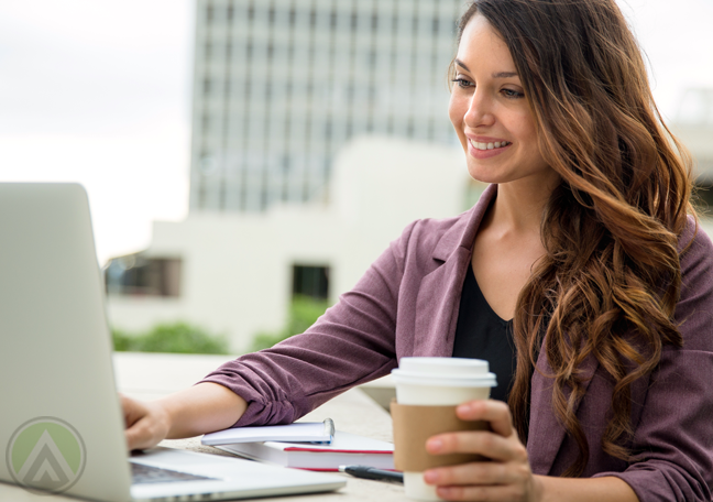 smiling-brunetter-woman-holding-coffee-cup-using-laptop