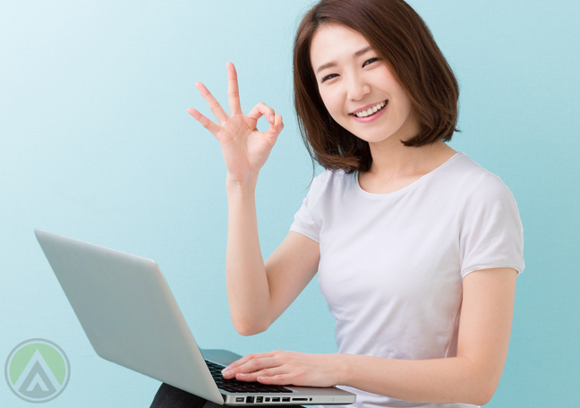 smiling-female-Asian-using-laptop-excellent-hand-sign