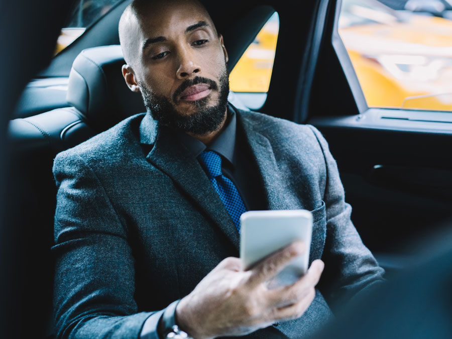 businessman watching online video on phone inside car