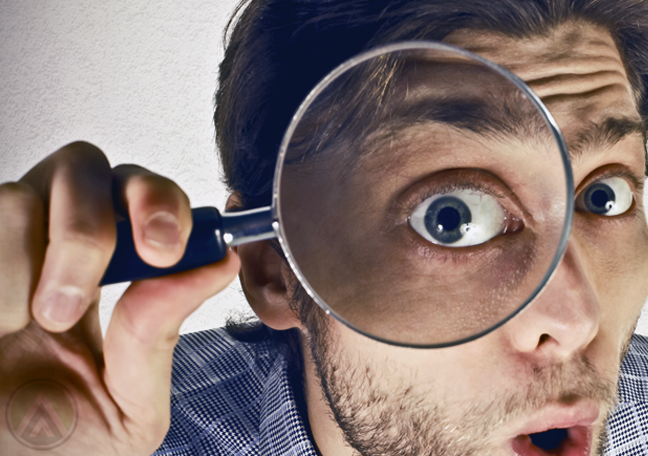 surprised-male-business-executive-looking-through-magnifying-lence