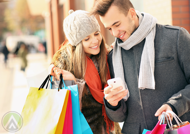 smiling-polish-poland-couple-with-shopping-bags-using-smartphone