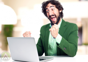 excited-bearded-man-in-green-coat-looking-at-laptop