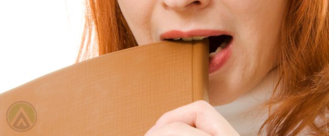 redhead-woman-biting-into-book-journal