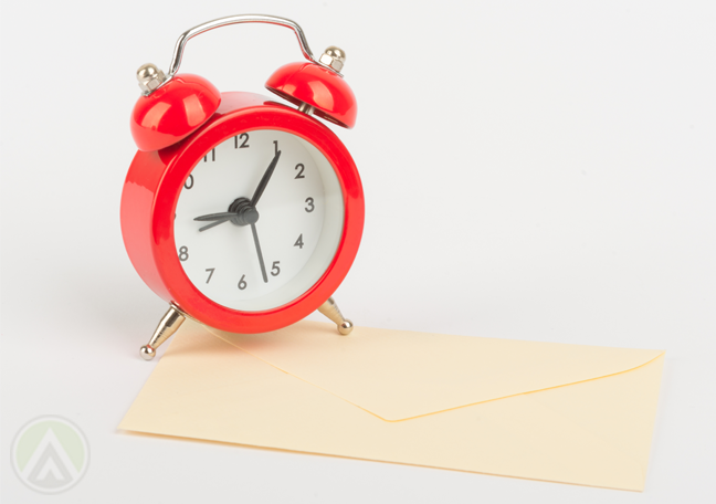 red-alarm-clock-on-yellowing-letter-envelope