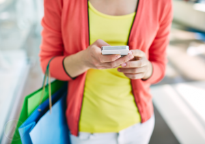 woman-with-shopping-bags-looking-at-smartphone