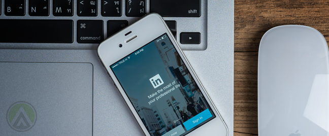 LinkedIn-mobile-app-on-iPhone-on-open-Macbook-keyboard-next-to-might-mouse