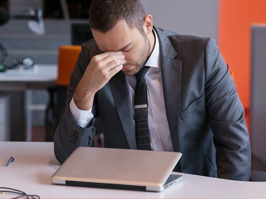 frustrated businessman with headache by laptop