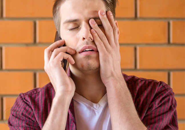 frustrated-man-on-phone-call-against-brick-wall