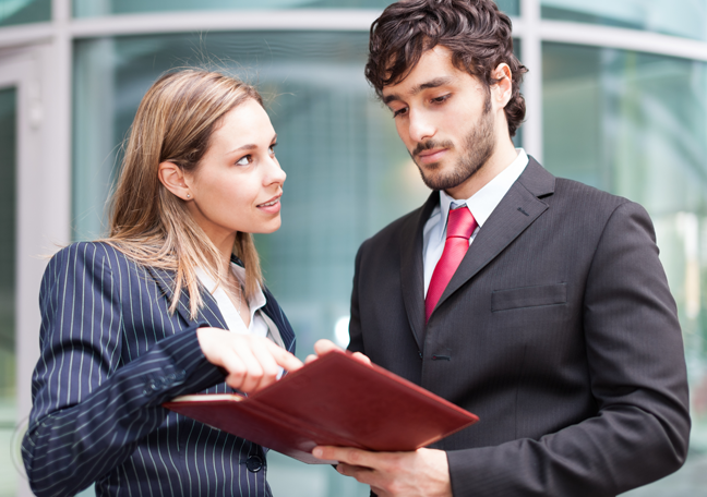 male-female-coworkers-reading-printed-report