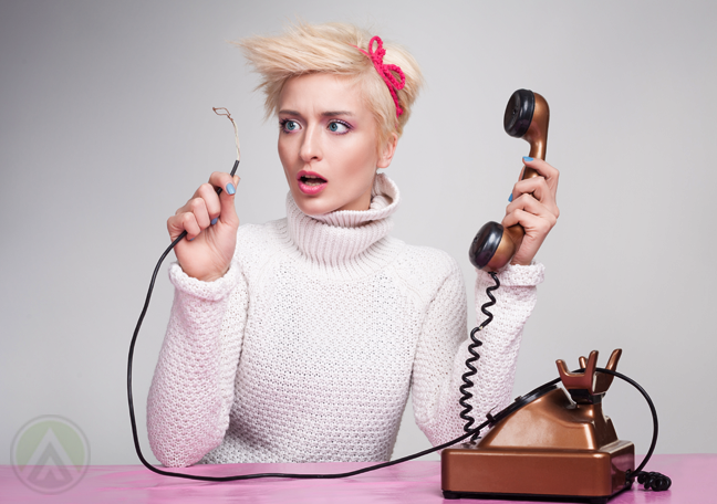 shocked-woman-holding-telephone-looking-at-disconnected-phone-cable