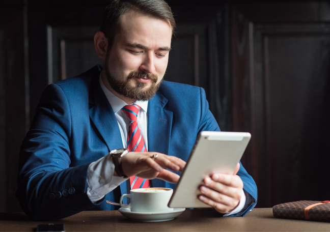 bearded-businessman-looking-reading-tablet-having-coffee
