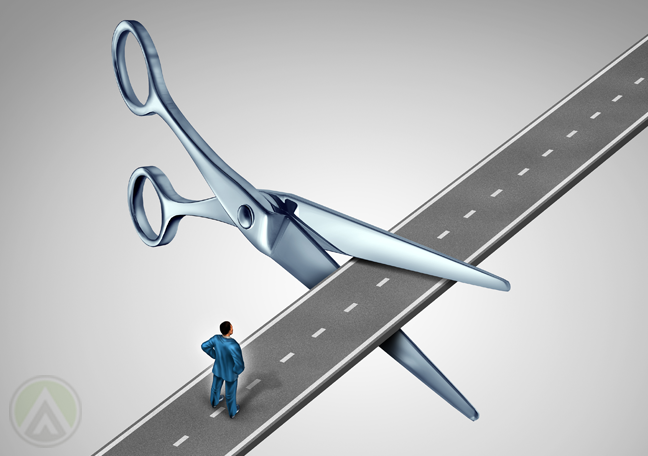 businessman-in-road-barred-by-giant-scissors