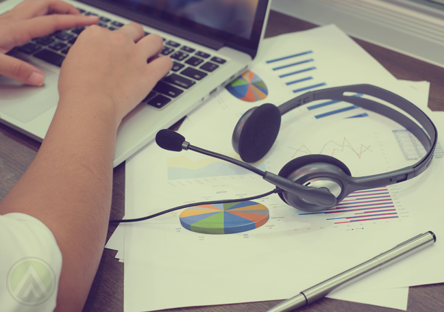 hand-typing-on-laptop-with-call-center-headset-printed-business-reports