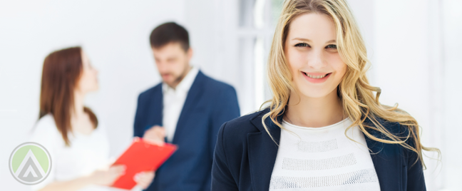 smiling-female-employee-with-coworkers-chatting-in-the-back