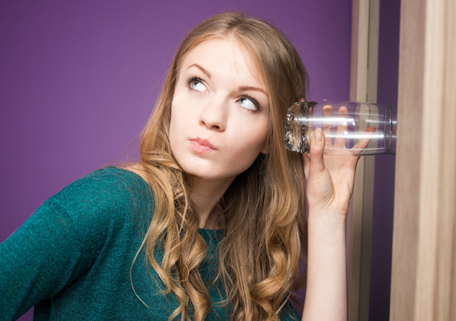 woman-listening-to-wall-with-glass