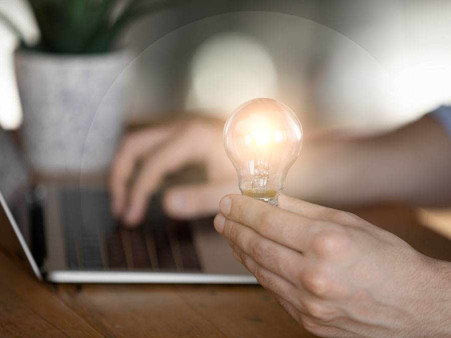 great customer service emails cx agent writing email on laptop holding bright lightbulb