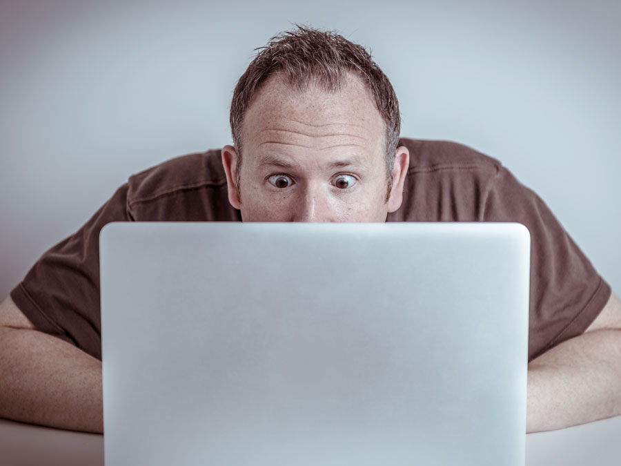 surprised man staring at laptop