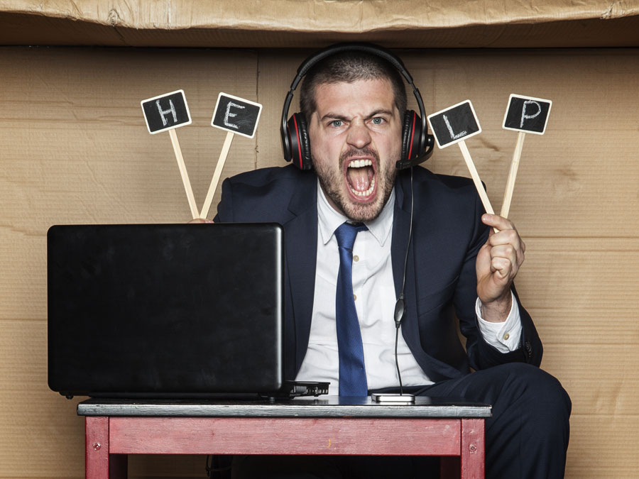 angry call center agent working in cardboard box holding help sign