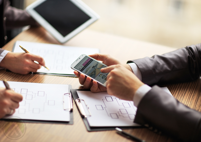 business team huddled in meeting using tablet smartphone