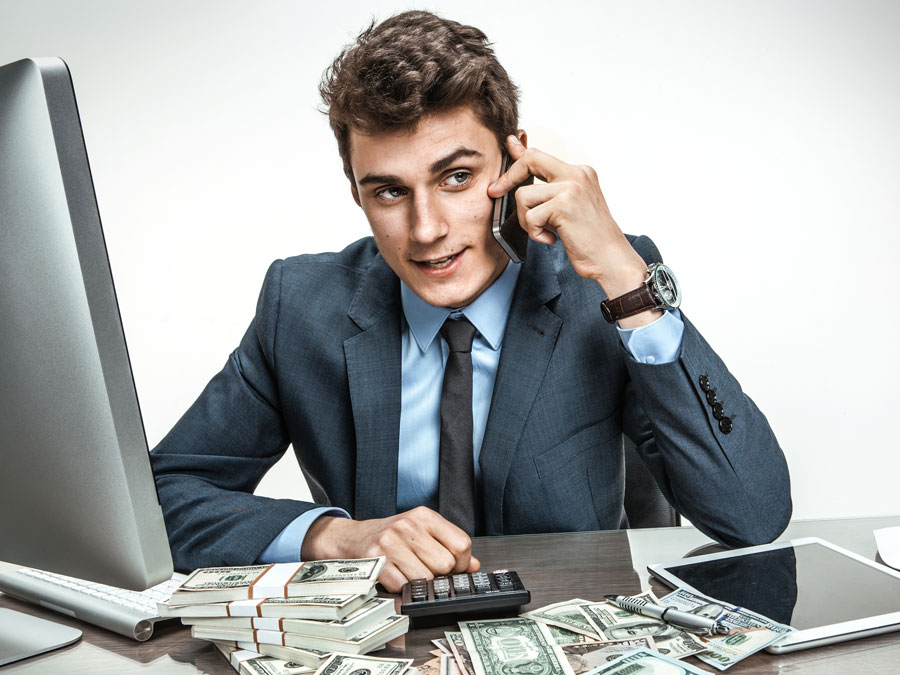 confident businessman on the phone at his office table with computer money calculator
