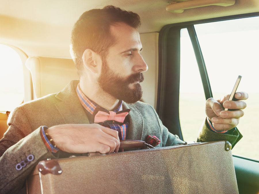 gentleman with luggage using smartphone in car