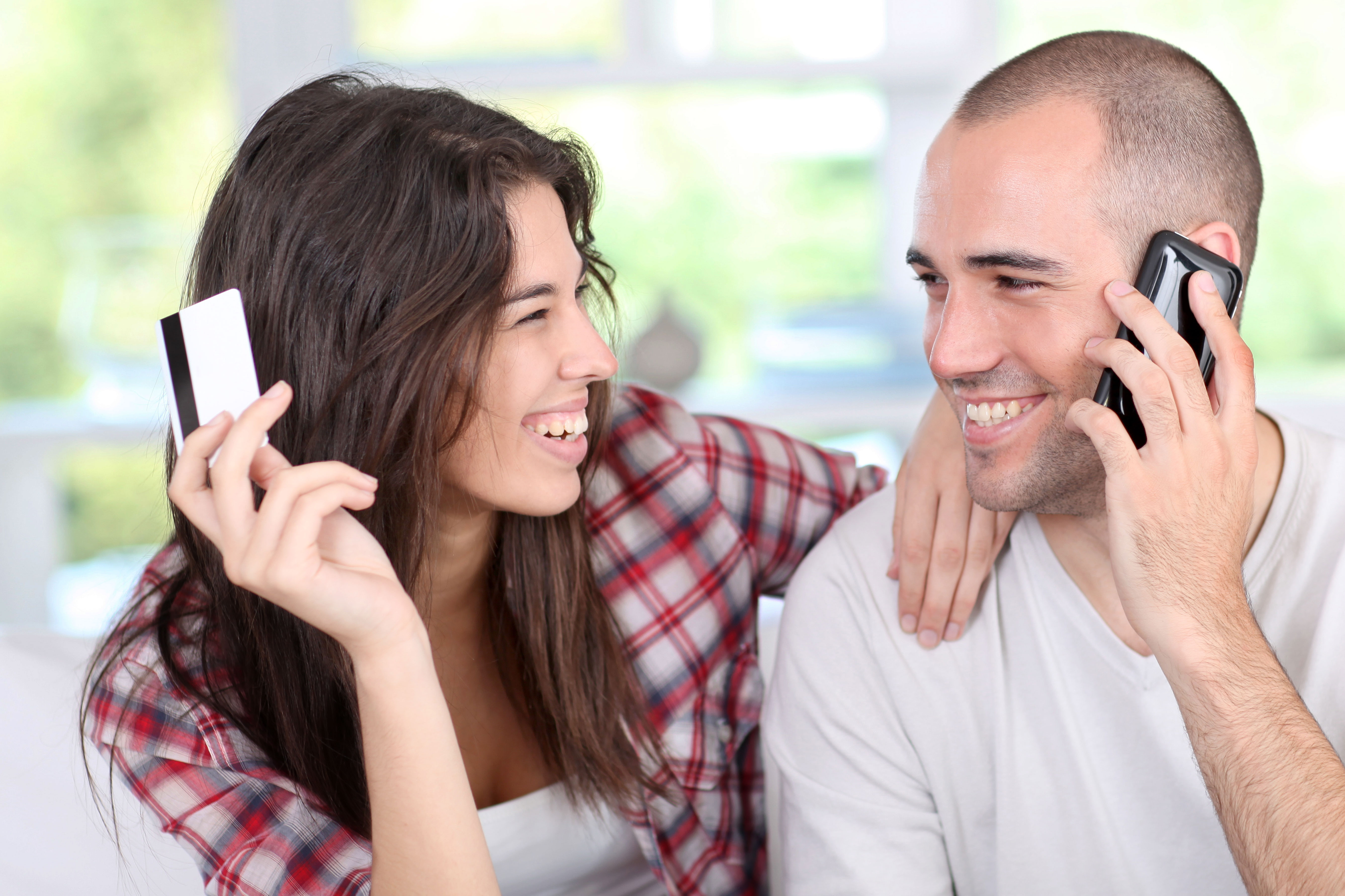 laughing couple on the phone with credit card online retail ecommerce
