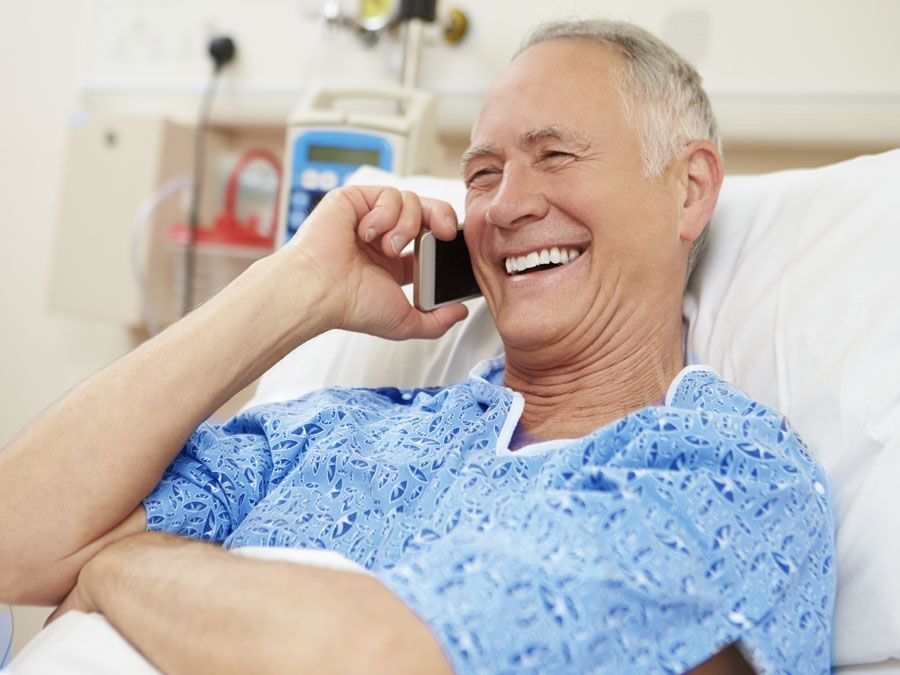senior gentleman in hospital bed using smartphone